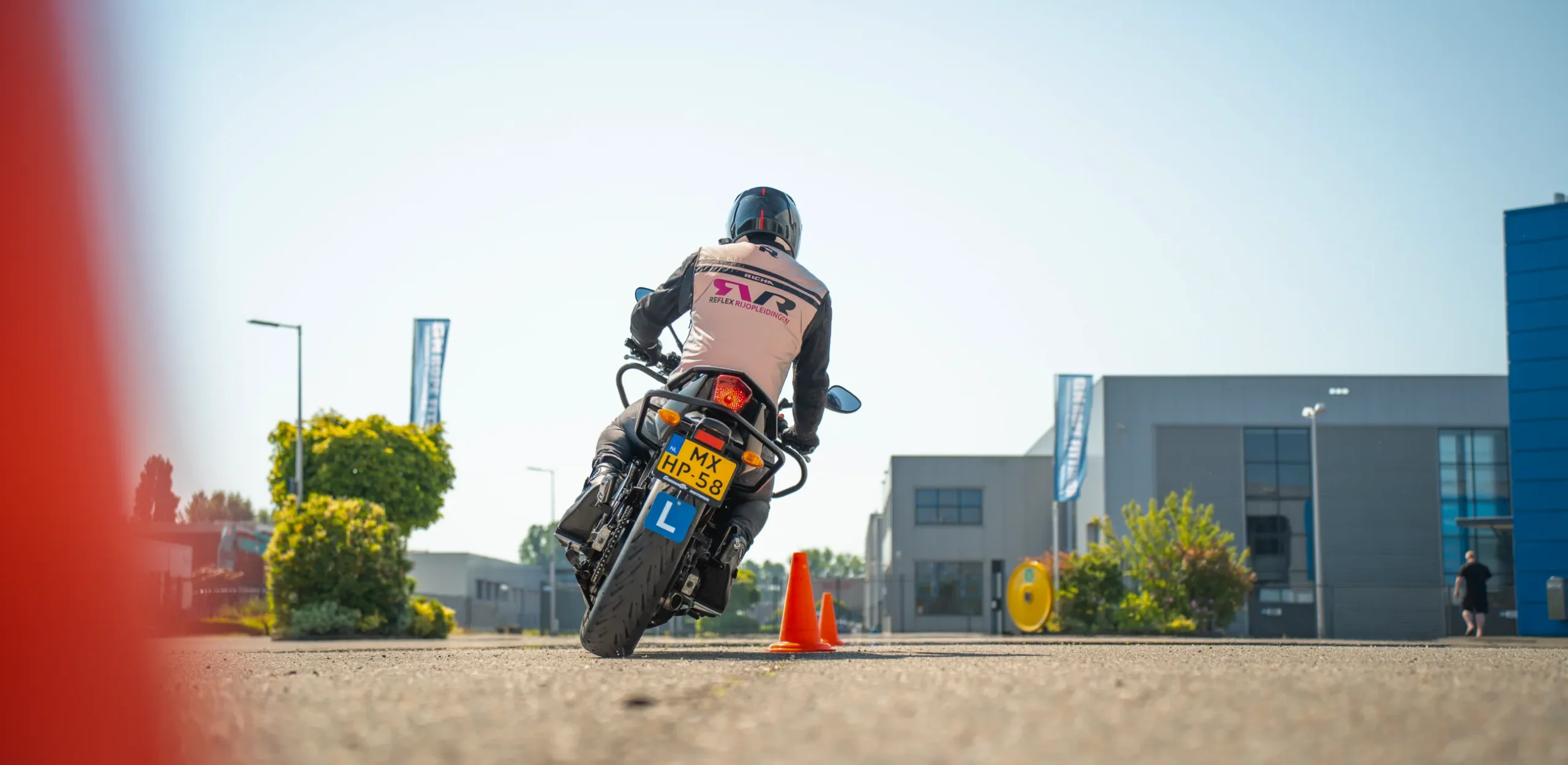 Een leerling van Reflex Rijopleidingen in Woerden oefent voertuigbeheersing (AVB) op de lesmotor tussen oranje pionnen.
